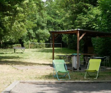 Espace pelouse avec chaises longues et pergola au Camping Onlycamp Le Pré