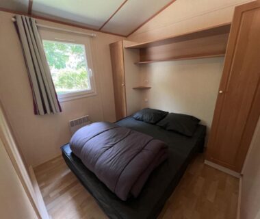 Chambre avec lit double et rangements dans le mobile home du Camping Onlycamp Le Pré