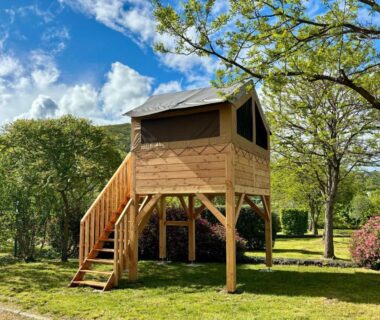 Pelouse avec cabane sur pilotis et escalier au camping Onlycamp Pierre et Sources