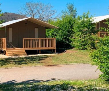 Terrasse de mobil-home sur pelouse ombragée au Camping Onlycamp Pierre & Sources