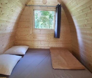 Intérieur de pod en bois avec matelas et fenêtre au Camping Onlycamp Port Sainte Marie