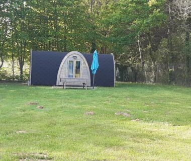 Pelouse avec pod en bois et parasol bleu au Camping Onlycamp Port Sainte Marie