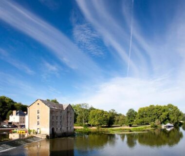 Bord de rivière avec bâtiment et reflets sur l'eau au Camping Onlycamp Port Sainte Marie