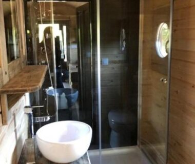 Salle de bain en bois avec douche vitrée et vasque dans le Camping Onlycamp du Rouergue