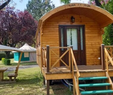 Espace herbeux avec chalet en bois terrasse et parasol au Camping Onlycamp du Rouergue