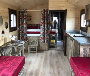 Intérieur en bois avec lits simples et kitchenette au Camping Onlycamp du Rouergue