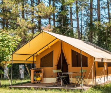 Tente safari sur plateforme entourée de pins au Camping Onlycamp la Rochette