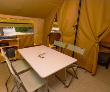 Intérieur de tente avec table et chaises au Camping Onlycamp la Rochette