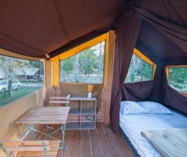 Intérieur de tente avec lit et coin repas au Camping Onlycamp la Rochette