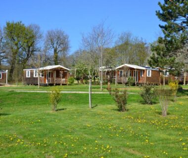 Prairie verte avec chalets en bois au Camping Padimadour