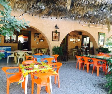 Terrasse ombragée avec tables et chaises oranges au Camping Paduella