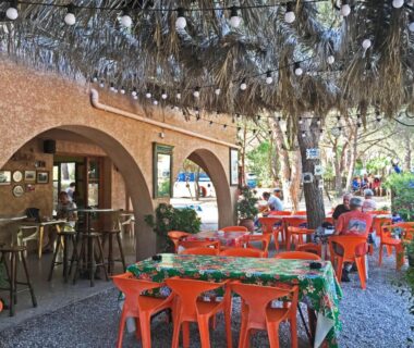 Terrasse ombragée avec tables et chaises orange au Camping Paduella