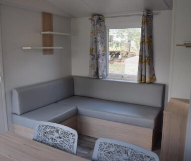 Intérieur du locatif avec banquette et table au Camping Paradella