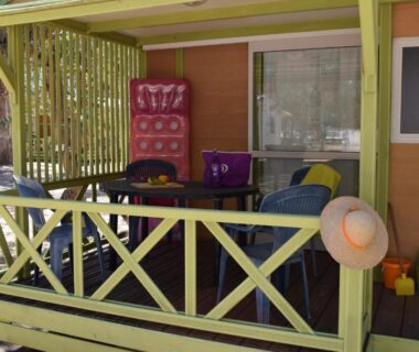 Terrasse couverte avec mobilier de jardin et chapeau accroché du Camping Paradella