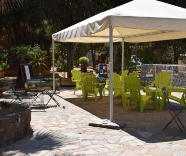 Terrasse avec tonnelle et chaises vertes au Camping Paradella