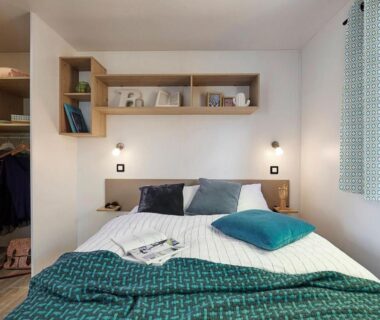 Chambre avec lit double et rangements au Camping Paradis Le Grand' R