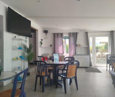 Salle commune avec tables et télévision dans le Camping Paradis Le Grand’ R