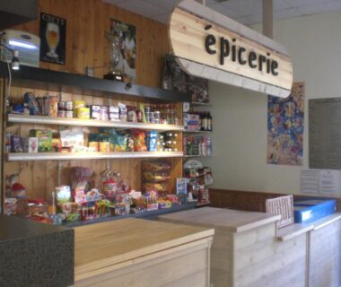 Dans l'épicerie comptoir et étagères de produits au Camping Paradis Le Royon