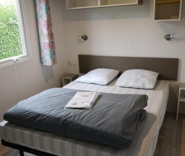 Chambre avec lit double étagères et fenêtre au Camping Paradis Les Galets de la Molliere