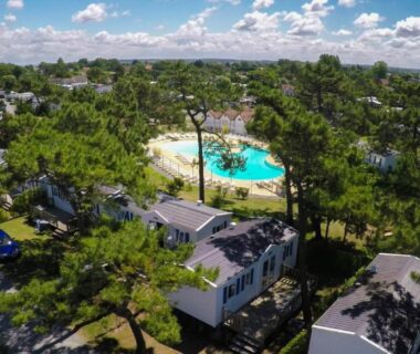 Piscine centrale entourée de mobil-homes et pins au Camping Paradis Les Galets de la Molliere