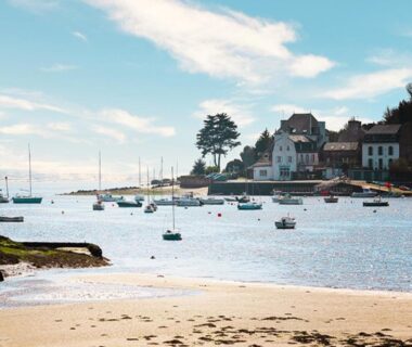 Plage avec bateaux et maisons en bord de mer au Camping Paradis du Quinquis