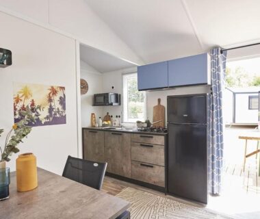 Intérieur du mobil-home avec cuisinette et coin repas au Camping Paradis le Rocher de la Granelle