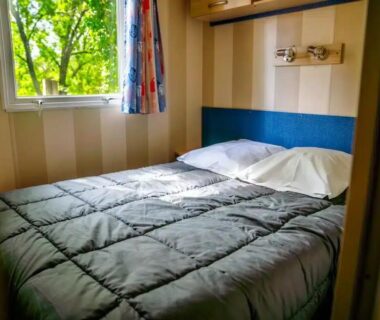 Chambre avec lit double et fenêtre dans le Camping Parc Bellevue Maeva