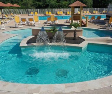 Piscine extérieure avec jets d'eau et transats au Camping Parc Bellevue Maeva