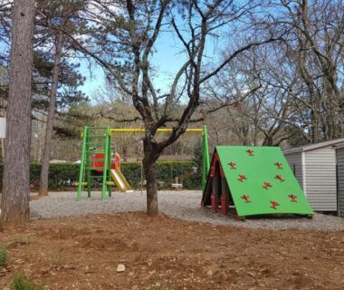 Aire de jeux avec mur d'escalade et structures ludiques près des mobil-homes au Camping Parc Saint Sauvayre