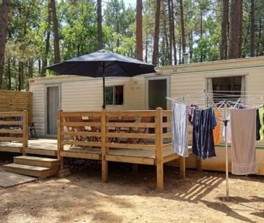 Sous-bois avec mobil-homes et terrasse en bois au Camping Parc Saint Sauvayre