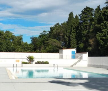 Piscine extérieure bordée d'un mur blanc au Camping Parc des 7 Fonts