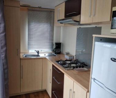 Cuisine équipée avec plaque de cuisson et réfrigérateur dans le mobil home du Camping Parc des 7 Fonts