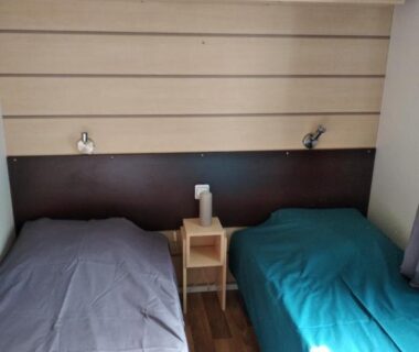 Chambre avec deux lits simples et chevet au Camping Parc des 7 Fonts