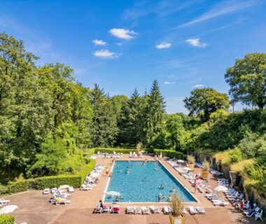 Piscine extérieure entourée d'arbres au Camping Parc des Roches