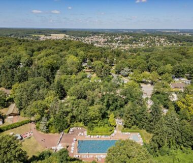 Piscine extérieure entourée d'arbres au Camping Parc des Roches