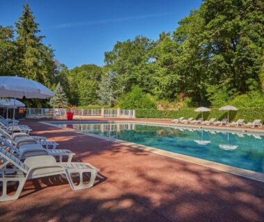 Piscine extérieure bordée de transats et parasols au Camping Parc des Roches