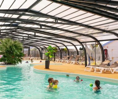 Piscine couverte avec transats et enfants nageant au Camping Park Er Lann