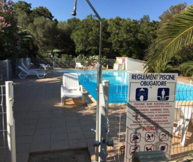 Piscine extérieure clôturée avec transats au Camping Pezza Cardo