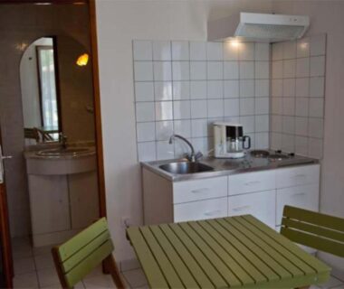 Coin cuisine avec table verte et kitchenette dans l'hébergement du Camping Porte des Vosges