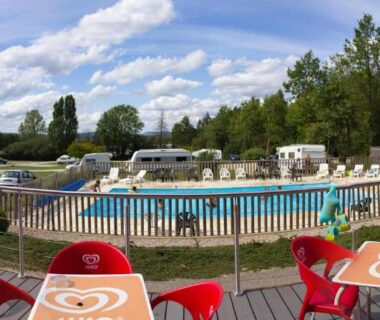 Terrasse avec tables et chaises près de la piscine au Camping Porte des Vosges