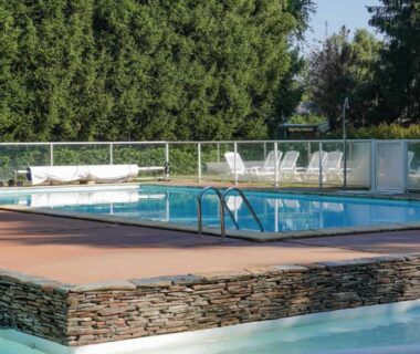Piscine extérieure avec transats et margelle en pierre au Camping Pradelongue