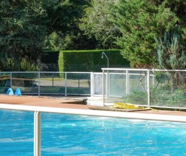 Bord de piscine avec barrière en verre et transat au Camping Pradelongue