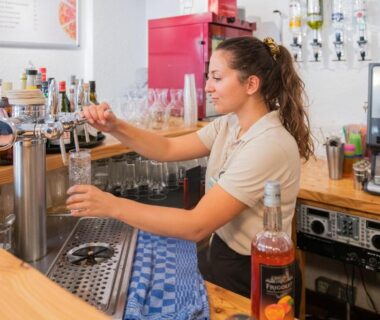 Comptoir de bar avec serveuse versant une boisson à la pression au Camping RCN Belledonne