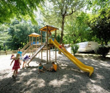 Aire de jeux ombragée avec toboggan et enfants au Camping RCN La Bastide en Ardèche