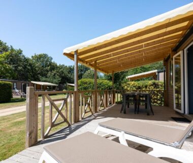 Terrasse couverte avec transats et table au Camping RCN La Ferme du Latois