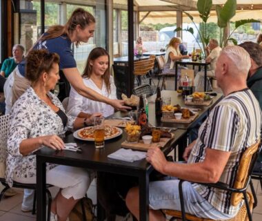 Terrasse couverte avec convives et serveuse au Camping RCN Port l'Epine