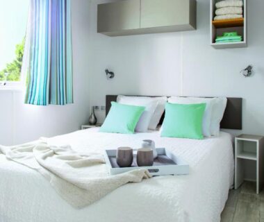 Chambre intérieure avec lit double et coussins du Camping Resort Les Champs Blancs