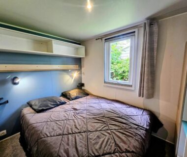 Chambre avec lit double rangements et fenêtre au Camping Riva Bella
