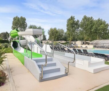 Espace piscine extérieur avec toboggan et transats au Camping Riva Bella