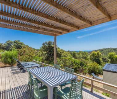 Terrasse en bois avec table, chaises et transats avec vue sur la mer au Camping Rondinara
